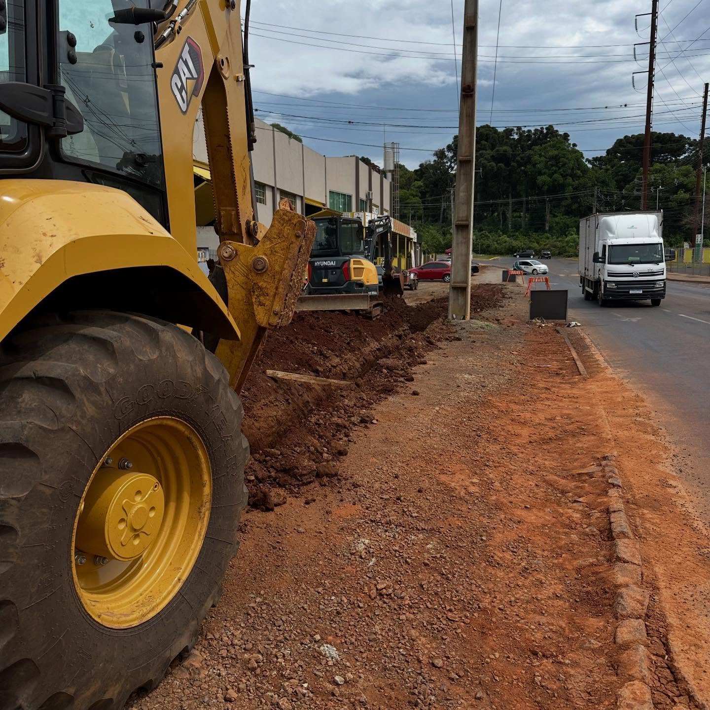 Escavação de vala em via urbana com sinalização e maquinário pesado