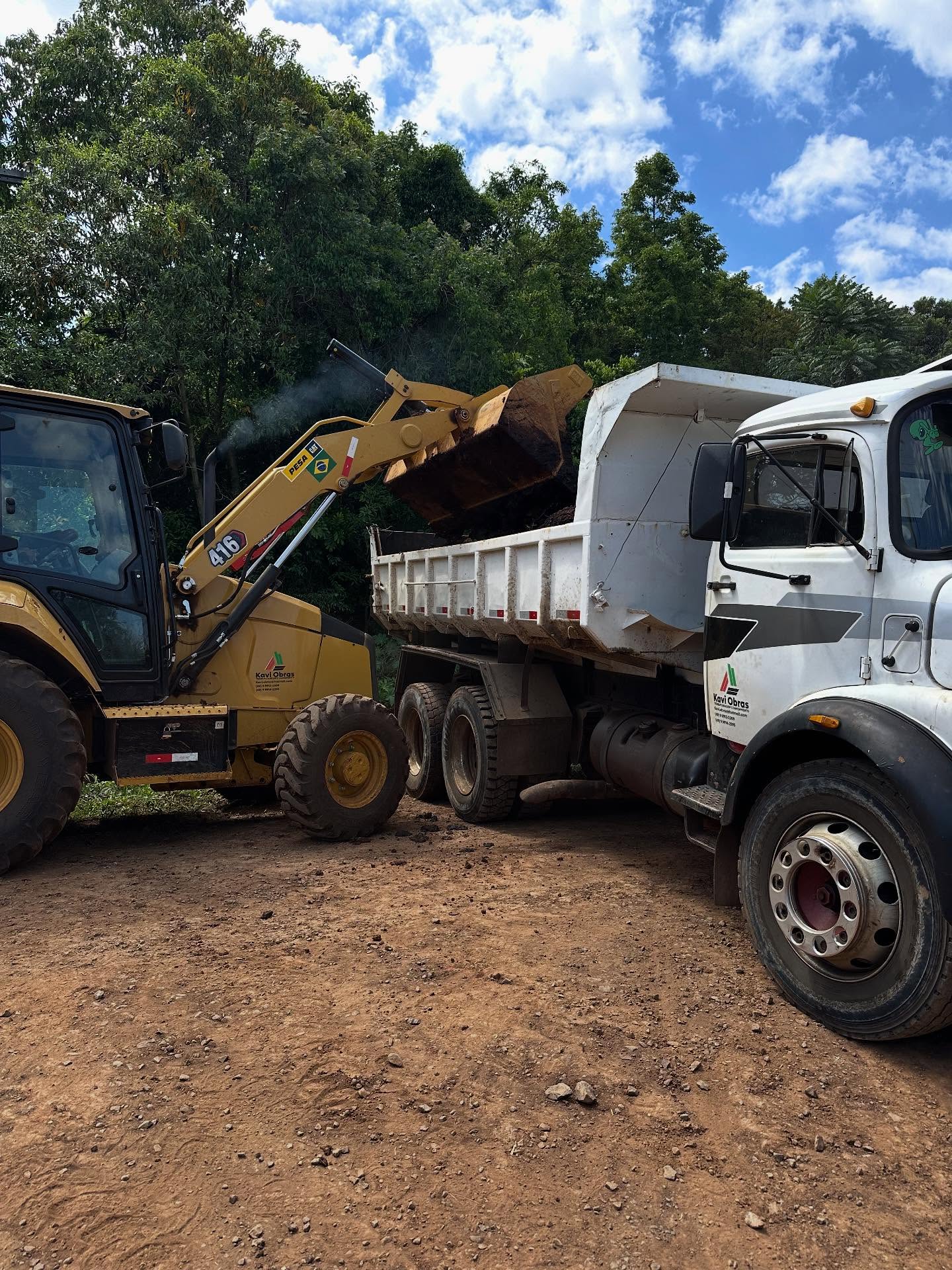 Retroescavadeira CAT carregando caminhão caçamba em obra de terraplanagem da Kavi Construções